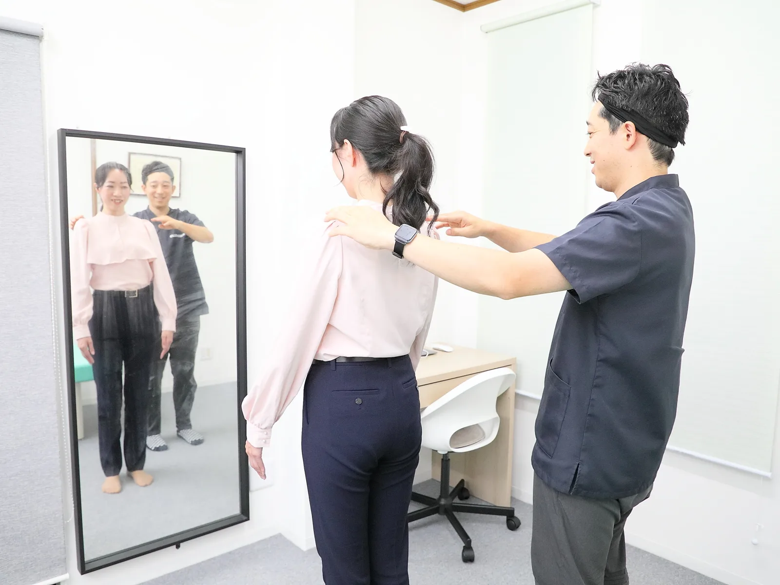 フィジオサロンキムラでの姿勢評価の様子。鏡の前でお客様の肩の位置を確認する木村